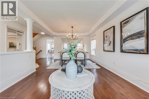 Dining space with a raised ceiling, dark wood finished floors, a chandelier, and decorative columns - 5811 Page Crescent, Burlington, ON - Indoor