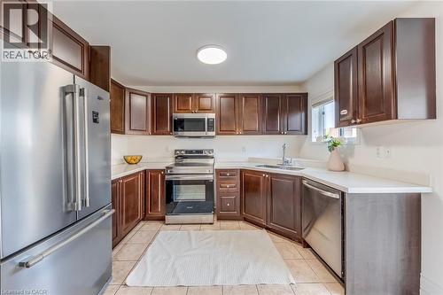 Kitchen featuring stainless steel appliances, light countertops, light tile patterned floors, and dark wood finish cabinetry - 5811 Page Crescent, Burlington, ON - Indoor Photo Showing Kitchen With Stainless Steel Kitchen