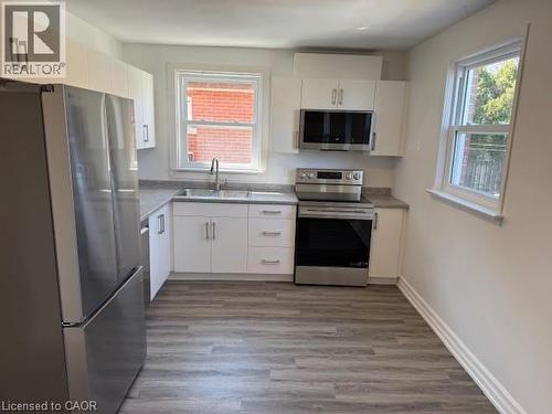 Kitchen featuring stainless steel appliances, white cabinets, and light wood-style floors - 322 Upper Gage Avenue, Hamilton, ON - Indoor Photo Showing Kitchen