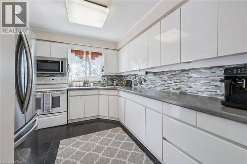 Kitchen with stainless steel appliances, white cabinets, backsplash, and dark countertops - 55 Ralgreen Crescent, Kitchener, ON - Indoor Photo Showing Kitchen