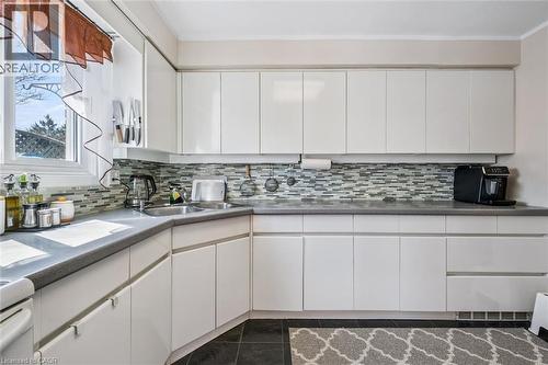 Kitchen with white cabinets, backsplash, and dark tile patterned flooring - 55 Ralgreen Crescent, Kitchener, ON - Indoor Photo Showing Kitchen With Double Sink