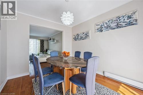 Dining area featuring suspended lighting, wood-type flooring, a baseboard heating unit, and crown molding - 55 Ralgreen Crescent, Kitchener, ON - Indoor Photo Showing Dining Room