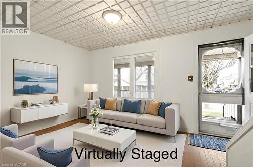 This inviting living area features hardwood floors, white walls, and a distinctive textured ceiling with a central light fixture - 23 Frederick Avenue, Hamilton, ON - Indoor Photo Showing Living Room