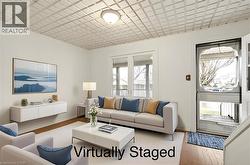 This inviting living area features hardwood floors, white walls, and a distinctive textured ceiling with a central light fixture - 