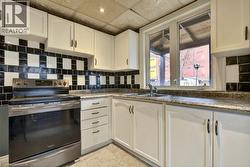 Kitchen with stainless steel range with electric stovetop, white cabinetry, an ornate ceiling, tasteful backsplash, and recessed lighting - 