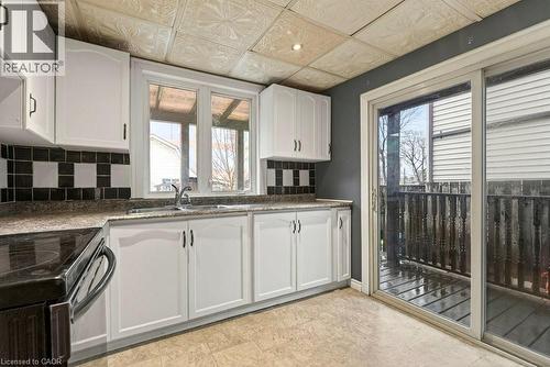 Kitchen featuring an ornate ceiling, decorative backsplash, white cabinetry, dark stone countertops, and black range with electric stovetop - 23 Frederick Avenue, Hamilton, ON -  Photo Showing Kitchen