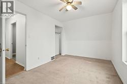 Unfurnished bedroom featuring light colored carpet, ceiling fan, and a closet - 