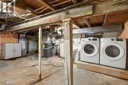 Unfinished below grade area featuring heating unit, gas water heater, and washer and clothes dryer - 