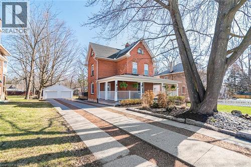 View of front facade featuring a porch, a detached garage, an outdoor structure, brick siding, and a chimney - 120 Caithness Street E, Caledonia, ON - Outdoor With Deck Patio Veranda