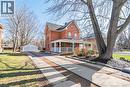 View of front facade featuring a porch, a detached garage, an outdoor structure, brick siding, and a chimney - 120 Caithness Street E, Caledonia, ON  - Outdoor With Deck Patio Veranda 