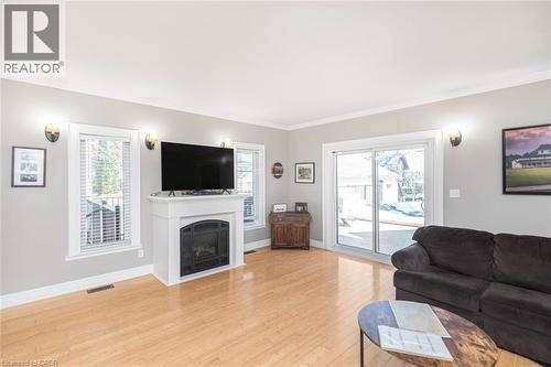 Living room featuring light wood-type flooring, crown molding, healthy amount of natural light, and a fireplace - 120 Caithness Street E, Caledonia, ON - Indoor Photo Showing Living Room With Fireplace