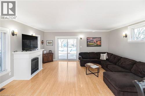 Living room featuring light wood-style floors, plenty of natural light, ornamental molding, and a fireplace - 120 Caithness Street E, Caledonia, ON - Indoor Photo Showing Living Room With Fireplace