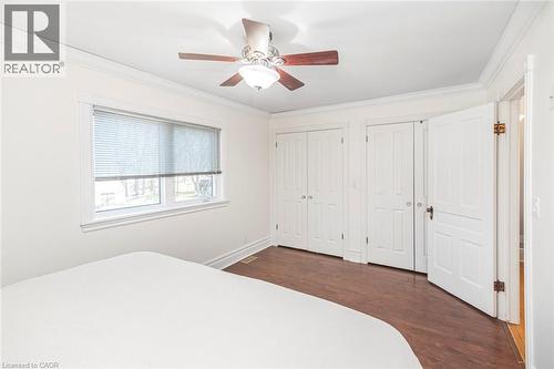 Unfurnished bedroom with two closets, crown molding, dark wood-style floors, and ceiling fan - 120 Caithness Street E, Caledonia, ON - Indoor Photo Showing Bedroom