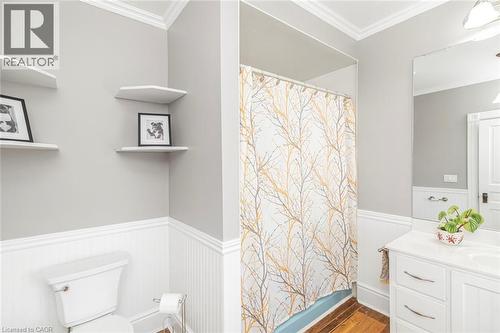 Bathroom featuring crown molding, a wainscoted wall, vanity, dark wood-style flooring, and shower / bath combination with curtain - 120 Caithness Street E, Caledonia, ON - Indoor Photo Showing Bathroom