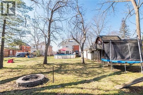 View of green lawn with a fire pit, a trampoline, an outdoor pool, and a residential view - 120 Caithness Street E, Caledonia, ON - Outdoor