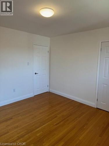 Unfurnished bedroom with wood-type flooring and baseboards - 31 Adair Avenue, Hamilton, ON - Indoor Photo Showing Other Room