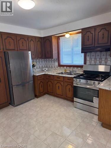 Kitchen with stainless steel appliances, light countertops, and dark wood finish cabinetry - 31 Adair Avenue, Hamilton, ON - Indoor Photo Showing Kitchen With Double Sink