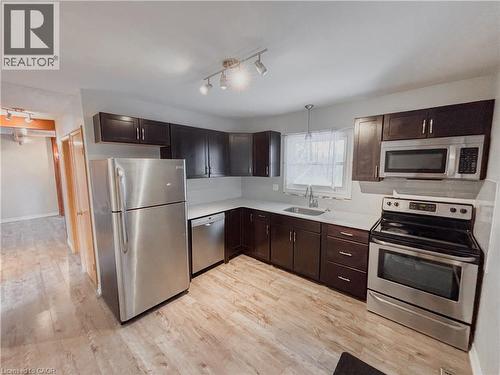 Kitchen featuring rail lighting, stainless steel appliances, dark wood finish cabinets, light countertops, and light wood finished floors - 122 Weber Street S, Waterloo, ON - Indoor Photo Showing Kitchen