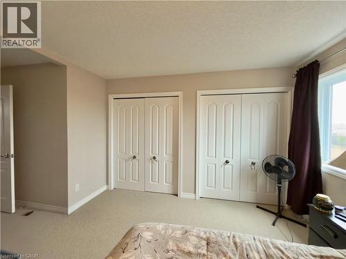 Bedroom with multiple closets, light carpet, and a textured ceiling - 101 Robert Simone Way, Ayr, ON - Indoor Photo Showing Bedroom