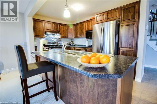 Kitchen featuring pendant lighting, a kitchen island with sink, a kitchen breakfast bar, sink, and stainless steel appliances - 101 Robert Simone Way, Ayr, ON - Indoor Photo Showing Kitchen With Double Sink