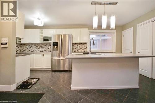 Kitchen featuring stainless steel appliances, white cabinets, an island with sink, hanging light fixtures, and open shelves - 61 Bosworth Crescent Unit# Upper, Kitchener, ON - Indoor Photo Showing Kitchen With Stainless Steel Kitchen