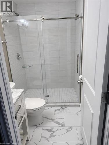 This bathroom features a contemporary shower with a glass sliding door and light-colored tiled walls - 61 Bosworth Crescent Unit# Upper, Kitchener, ON - Indoor Photo Showing Bathroom