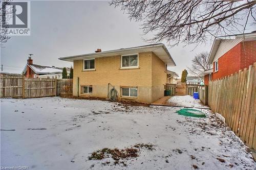 Snow covered back of property featuring a fenced backyard, brick siding, and a chimney - 61 Bosworth Crescent Unit# Upper, Kitchener, ON - Outdoor With Exterior