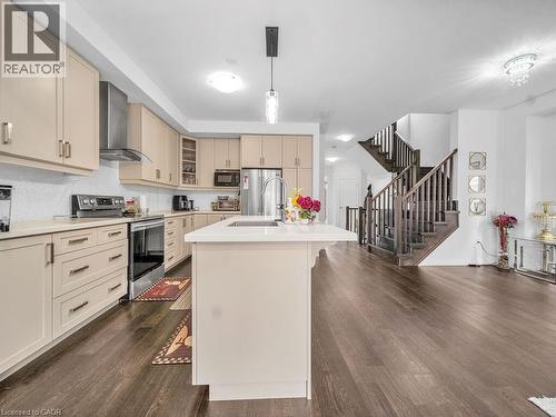 Kitchen with cream cabinets, stainless steel appliances, glass insert cabinets, an island with sink, and dark wood-style floors - 30 Times Square Boulevard, Hamilton, ON - Indoor Photo Showing Kitchen With Upgraded Kitchen