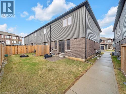 Rear view of property with brick siding, entry steps, an outdoor fire pit, and a fenced backyard - 30 Times Square Boulevard, Hamilton, ON - Outdoor