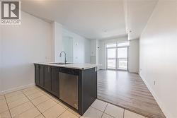 Kitchen featuring a peninsula, stainless steel dishwasher, light tile patterned flooring, open floor plan, and dark wood finish cabinetry - 