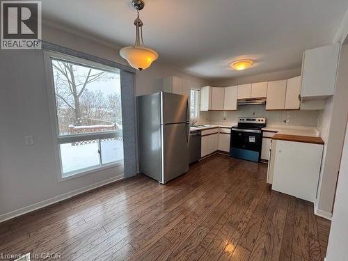 Kitchen with white cabinets, stainless steel appliances, decorative light fixtures, and dark wood-style flooring - 536 Thorndale Drive, Waterloo, ON - Indoor Photo Showing Kitchen