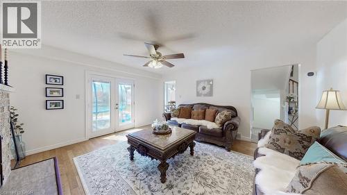 Living area with light wood-style floors, a textured ceiling, ceiling fan, french doors, and a fireplace with flush hearth - 330 Guelph Avenue, Cambridge, ON - Indoor Photo Showing Living Room With Fireplace