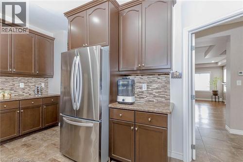 Kitchen with freestanding refrigerator, light stone countertops, and decorative backsplash - 2 Doon Creek Street, Kitchener, ON - Indoor Photo Showing Kitchen