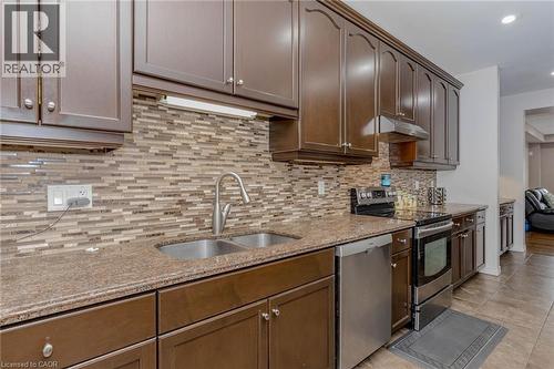 Kitchen featuring stainless steel appliances, light stone countertops, decorative backsplash, recessed lighting, and dark wood finish cabinetry - 2 Doon Creek Street, Kitchener, ON - Indoor Photo Showing Kitchen With Double Sink With Upgraded Kitchen