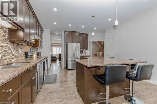 Kitchen with light stone counters, stainless steel appliances, a kitchen island, a kitchen breakfast bar, and dark wood finish cabinets - 2 Doon Creek Street, Kitchener, ON - Indoor Photo Showing Kitchen With Double Sink With Upgraded Kitchen