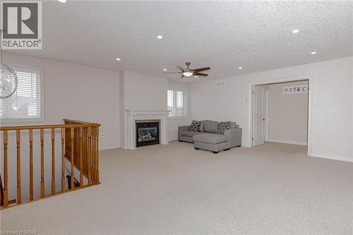 Unfurnished room featuring a textured ceiling, light carpet, an upstairs landing, a glass covered fireplace, and recessed lighting - 2 Doon Creek Street, Kitchener, ON - Indoor With Fireplace