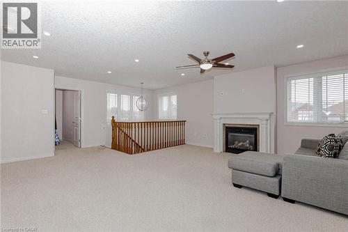 Living area with light carpet, ceiling fan, a textured ceiling, a glass covered fireplace, and recessed lighting - 2 Doon Creek Street, Kitchener, ON - Indoor Photo Showing Living Room With Fireplace