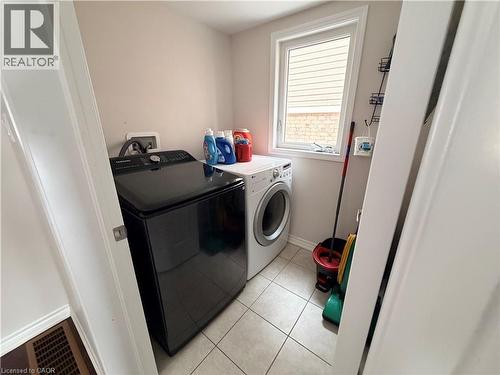 Laundry area with light tile patterned floors and washing machine and dryer - 31 Sofitel Drive, Kitchener, ON - Indoor Photo Showing Laundry Room