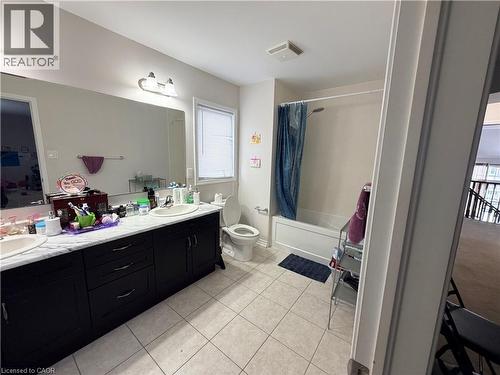Bathroom featuring double vanity, shower / bathtub combination with curtain, and light tile patterned floors - 31 Sofitel Drive, Kitchener, ON - Indoor Photo Showing Bathroom