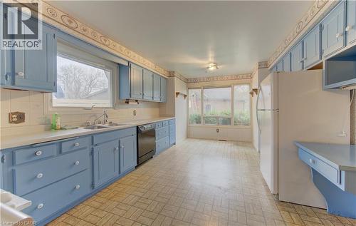 Kitchen featuring blue cabinetry, light countertops, brick patterned floors, freestanding refrigerator, and dishwasher - 190 Silvercrest Drive, Waterloo, ON - Indoor Photo Showing Kitchen