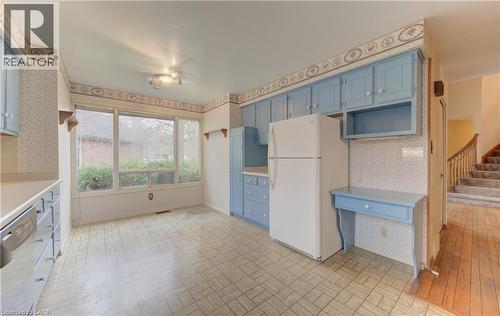 Kitchen featuring blue cabinetry, wallpapered walls, brick patterned floors, freestanding refrigerator, and dishwashing machine - 190 Silvercrest Drive, Waterloo, ON - Indoor