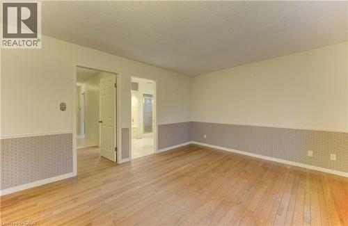 Unfurnished room featuring wallpapered walls, light wood-style floors, a wainscoted wall, and a textured ceiling - 190 Silvercrest Drive, Waterloo, ON - Indoor Photo Showing Other Room