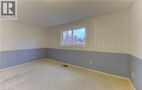 Carpeted empty room featuring wainscoting, wallpapered walls, and a textured ceiling - 190 Silvercrest Drive, Waterloo, ON - Indoor Photo Showing Other Room