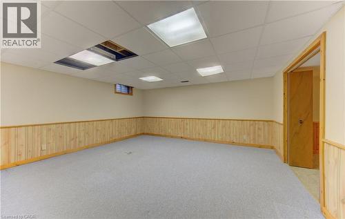 Empty room featuring a paneled ceiling, light carpet, and wainscoting - 190 Silvercrest Drive, Waterloo, ON - Indoor Photo Showing Basement