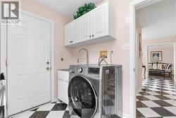 Laundry area featuring dark floors, washer / dryer, and cabinet space - 