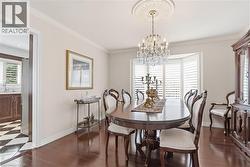 Dining room featuring ornamental molding, dark wood-type flooring, and hanging lights - 