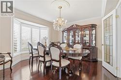 Dining room with dark wood-type flooring, suspended lighting, and ornamental molding - 