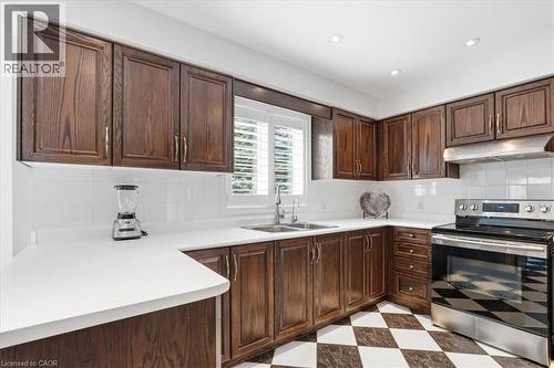 Kitchen with stainless steel range with electric cooktop, light flooring, light countertops, dark wood finish cabinets, and tasteful backsplash - 54 Woodcrest Court, Kitchener, ON - Indoor Photo Showing Kitchen With Double Sink