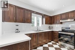 Kitchen with stainless steel range with electric cooktop, light flooring, light countertops, dark wood finish cabinets, and tasteful backsplash - 