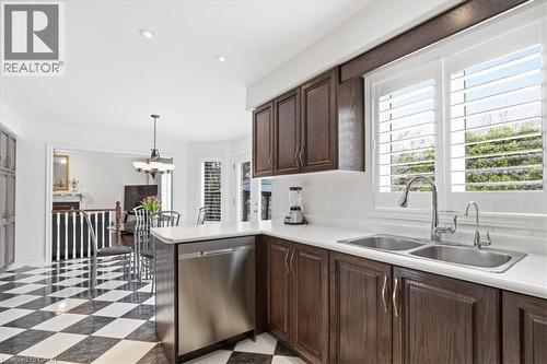 Kitchen with dark wood finish cabinets, stainless steel dishwasher, light countertops, and backsplash - 54 Woodcrest Court, Kitchener, ON - Indoor Photo Showing Kitchen With Double Sink